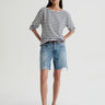 Woman wearing a striped shirt and denim shorts on a white background