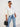 A woman modeling a cream-colored, oversized button-down shirt tied at the waist, paired with blue denim jeans, set against a plain white studio background.