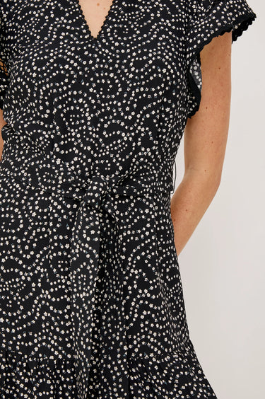 Black dress with white pattern worn by a person on a plain background