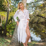 woman wearing the white Eyelet Trim Long White Shirt Dress leaning on a tree