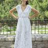 woman wearing a white maxi lace dress in front of a fence