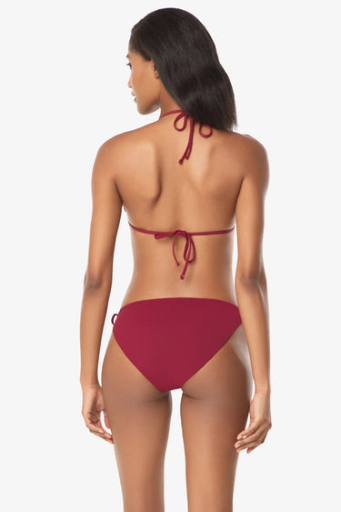 Rear view of a woman wearing a solid maroon red adjustable halter triangle bikini top and side-tie bikini bottoms, against a white background.