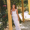 women wearing scallop crochet tank and maxi skirt leaning on a post with flowers in the background
