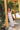 women wearing scallop crochet tank and maxi skirt leaning on a post with flowers in the background