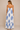 Woman wearing a white dress with blue shell patterns on a beige background