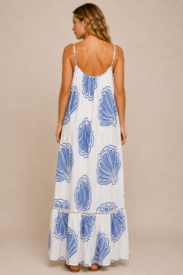 Woman wearing a white dress with blue shell patterns on a beige background