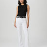 Woman wearing a black sleeveless top and white pants on a plain background