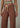 Brown pants with a striped crop top on a neutral background
