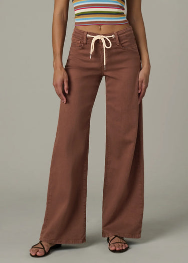 Person wearing brown wide-leg pants with a striped top on a neutral background