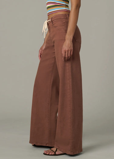 Person wearing brown wide-leg pants and a striped top on a neutral background