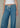 Person wearing blue jeans with a white top on a neutral background