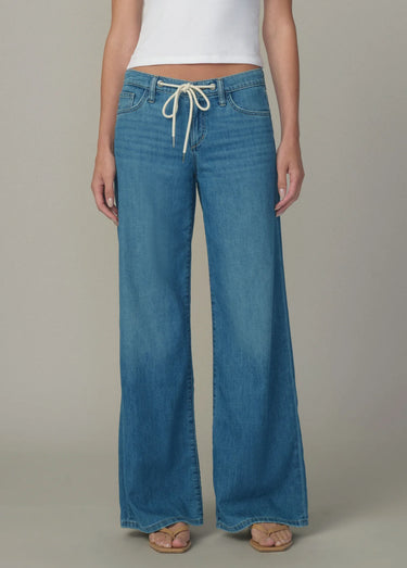 Blue jeans worn by a person on a neutral background