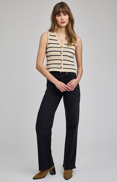 Woman wearing a striped sleeveless top and black pants on a gray background