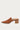 A single brown leather mule shoe with a pointed toe and a stacked wood-look block heel, shown in profile against a light gray background.
