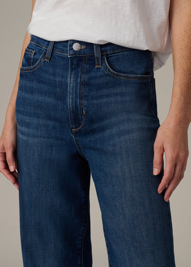 Person wearing blue jeans and a white shirt against a neutral background