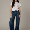 Woman wearing a white t-shirt and blue jeans on a plain background