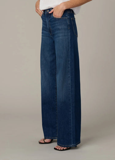 Person wearing blue jeans on a neutral background
