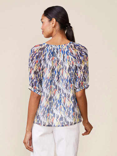 Woman wearing a colorful patterned blouse against a beige background