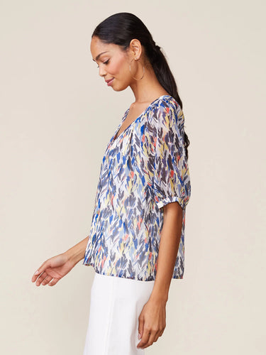 Woman wearing a colorful blouse against a beige background