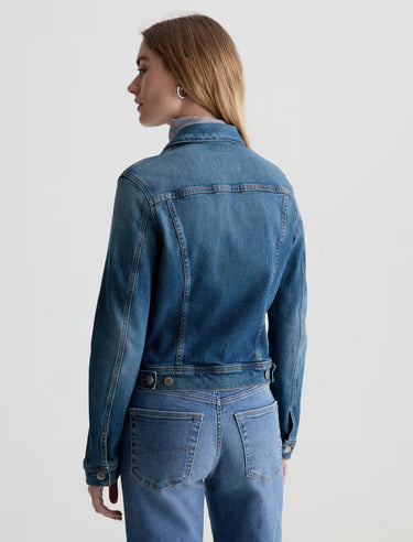 Person wearing a blue denim jacket and jeans on a white background