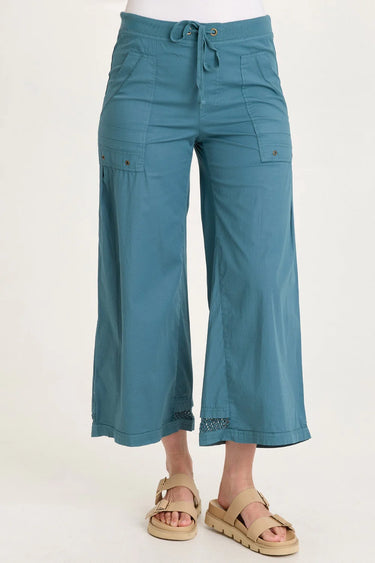 Teal capri pants worn by a person on a white background