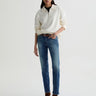 Person wearing a white sweater, blue jeans, and brown boots on a white background