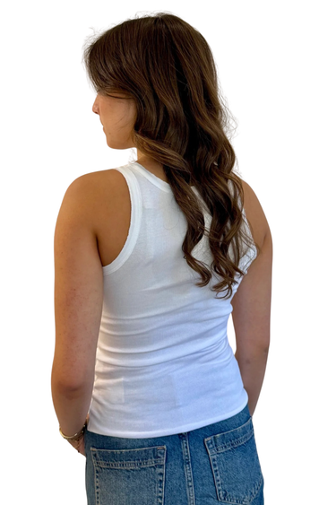 Woman wearing a white tank top and blue jeans on a white background