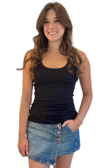 Woman wearing a black tank top and denim skirt on a white background