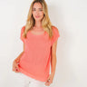 Woman wearing a coral top and white shorts on a white background