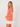Woman wearing a coral sweater over a white shirt on a plain background