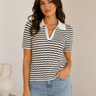 Woman wearing a black and white striped polo shirt with a plain background