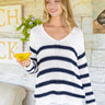 Woman wearing a white and navy striped sweater holding a glass of orange juice.